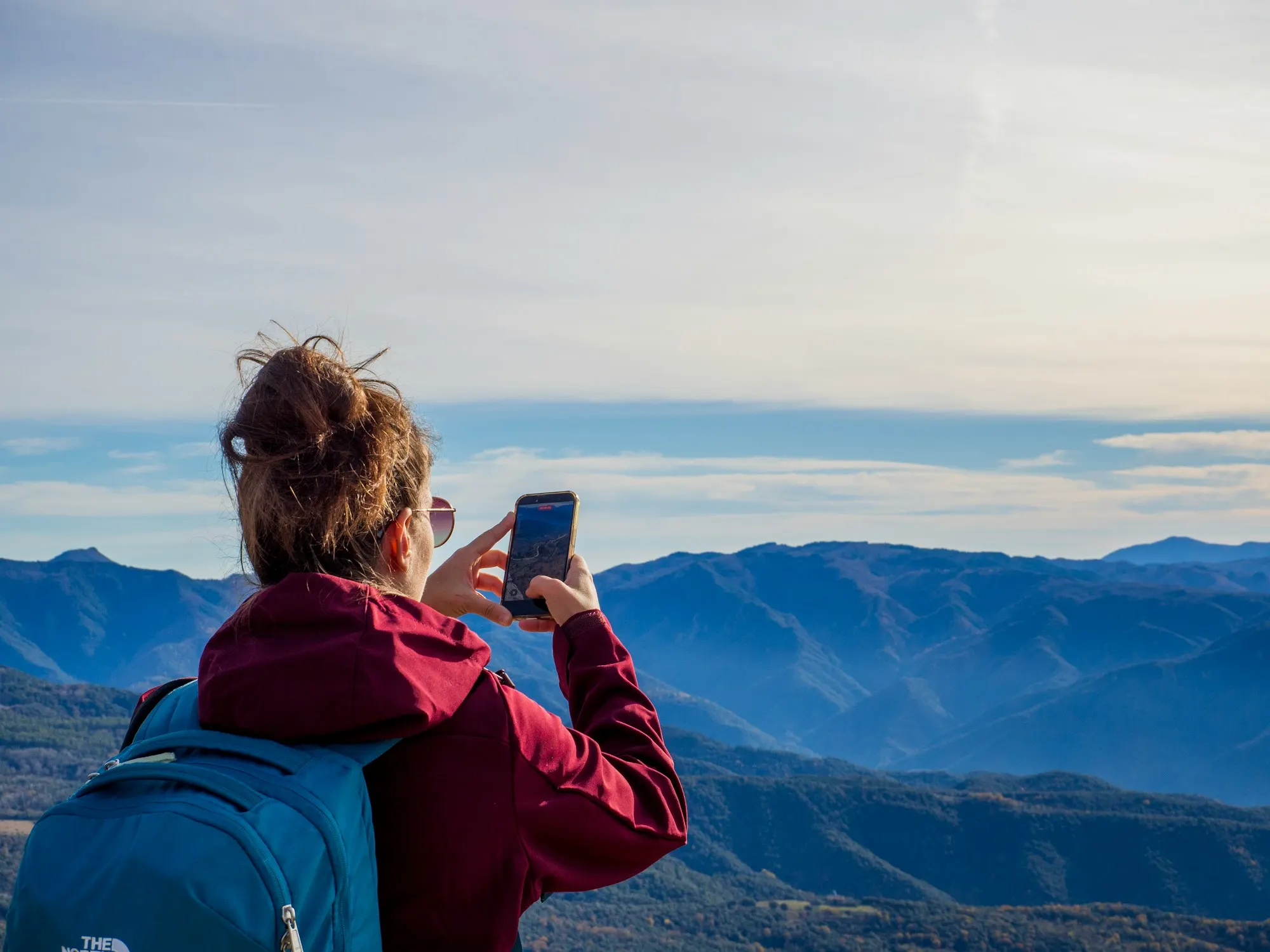 Traveller with a backpack photographing a mountain range with a smartphone