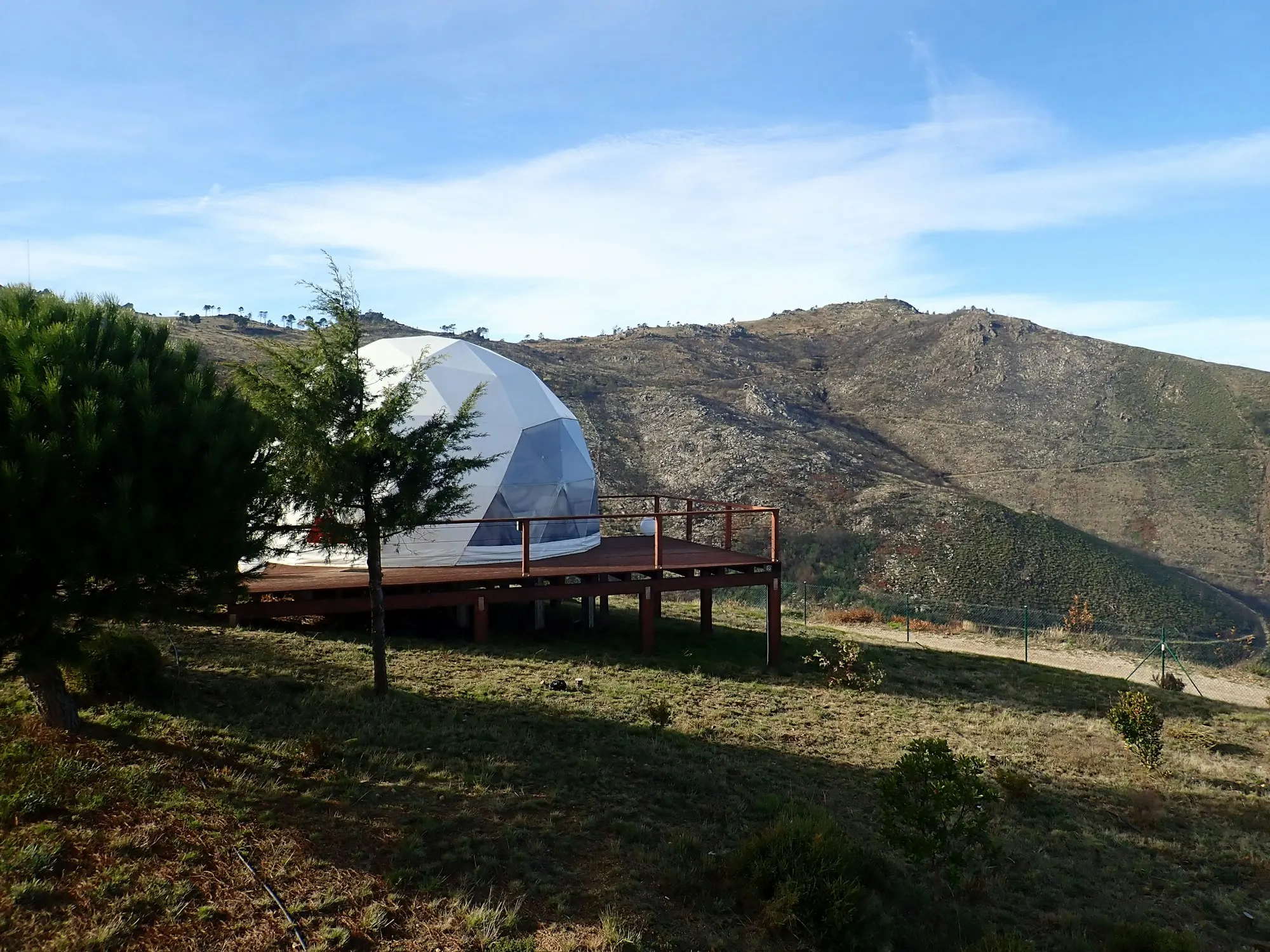 White glamping dome on a green hillside above a valley