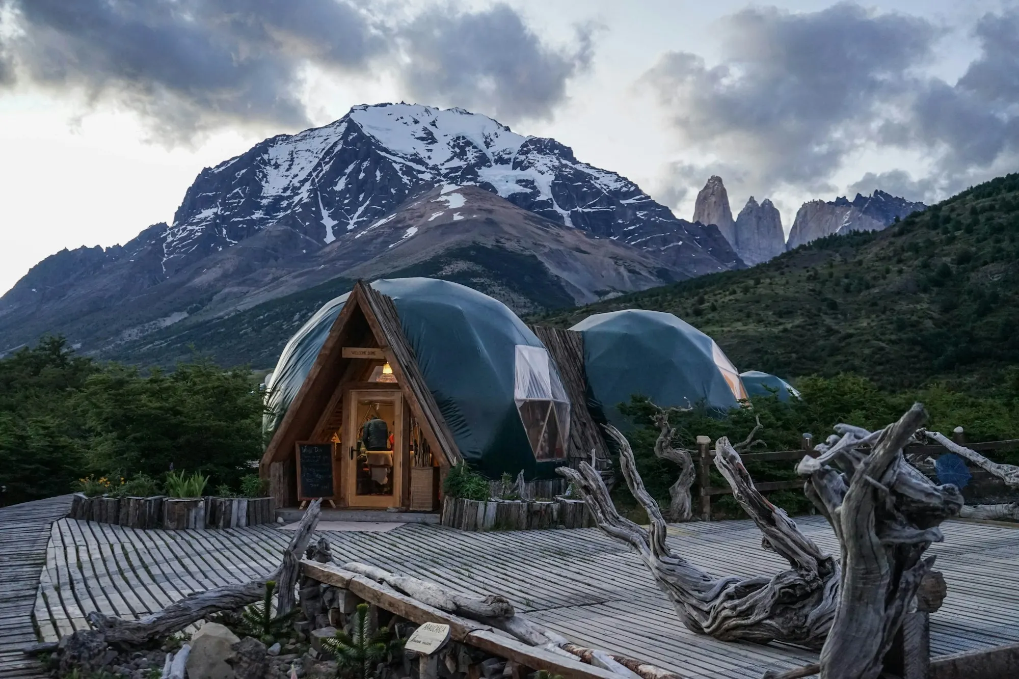 Wooden glamping domes at the foot of snow-capped granite peaks