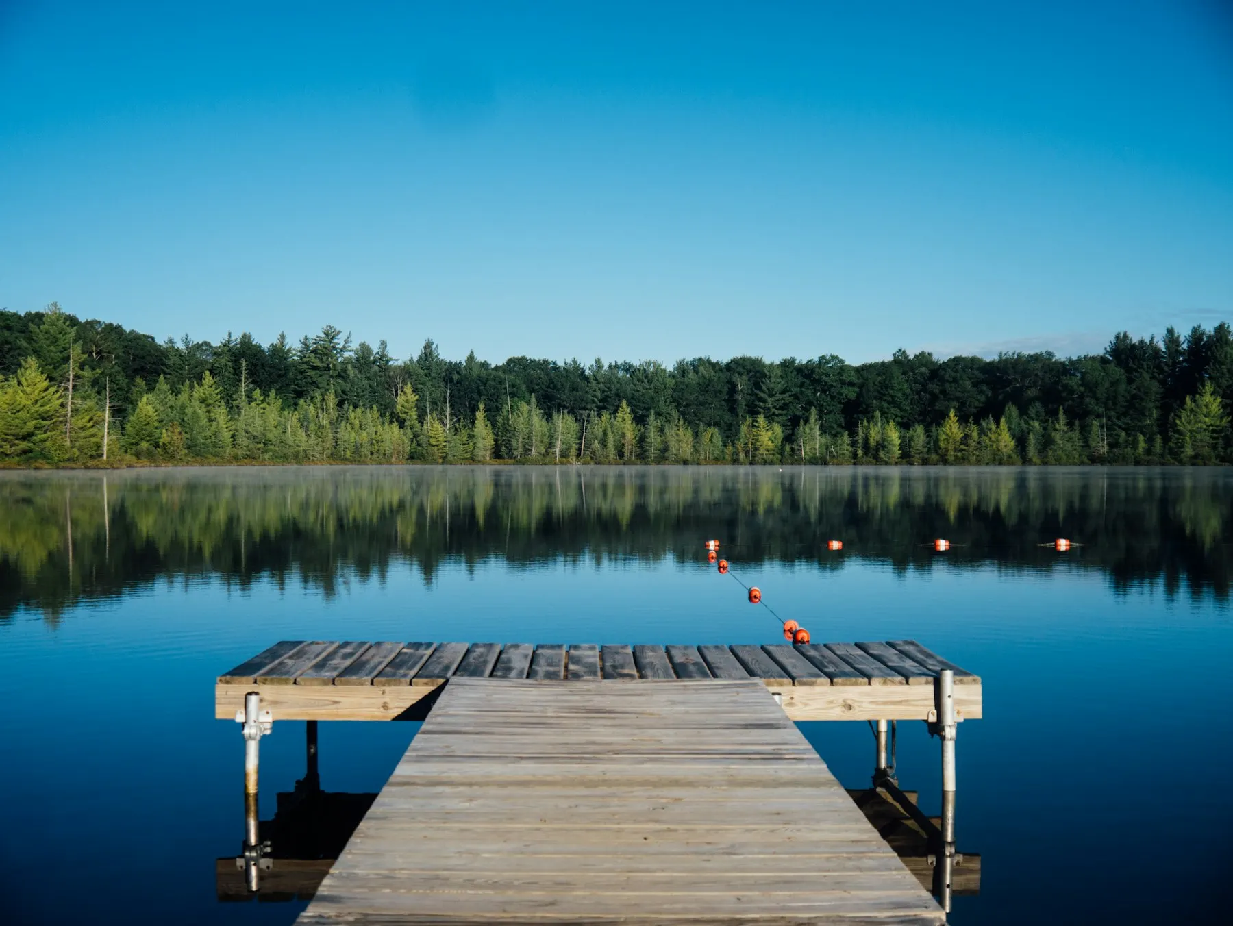 Wooden dock on a still mountain lake at dawn