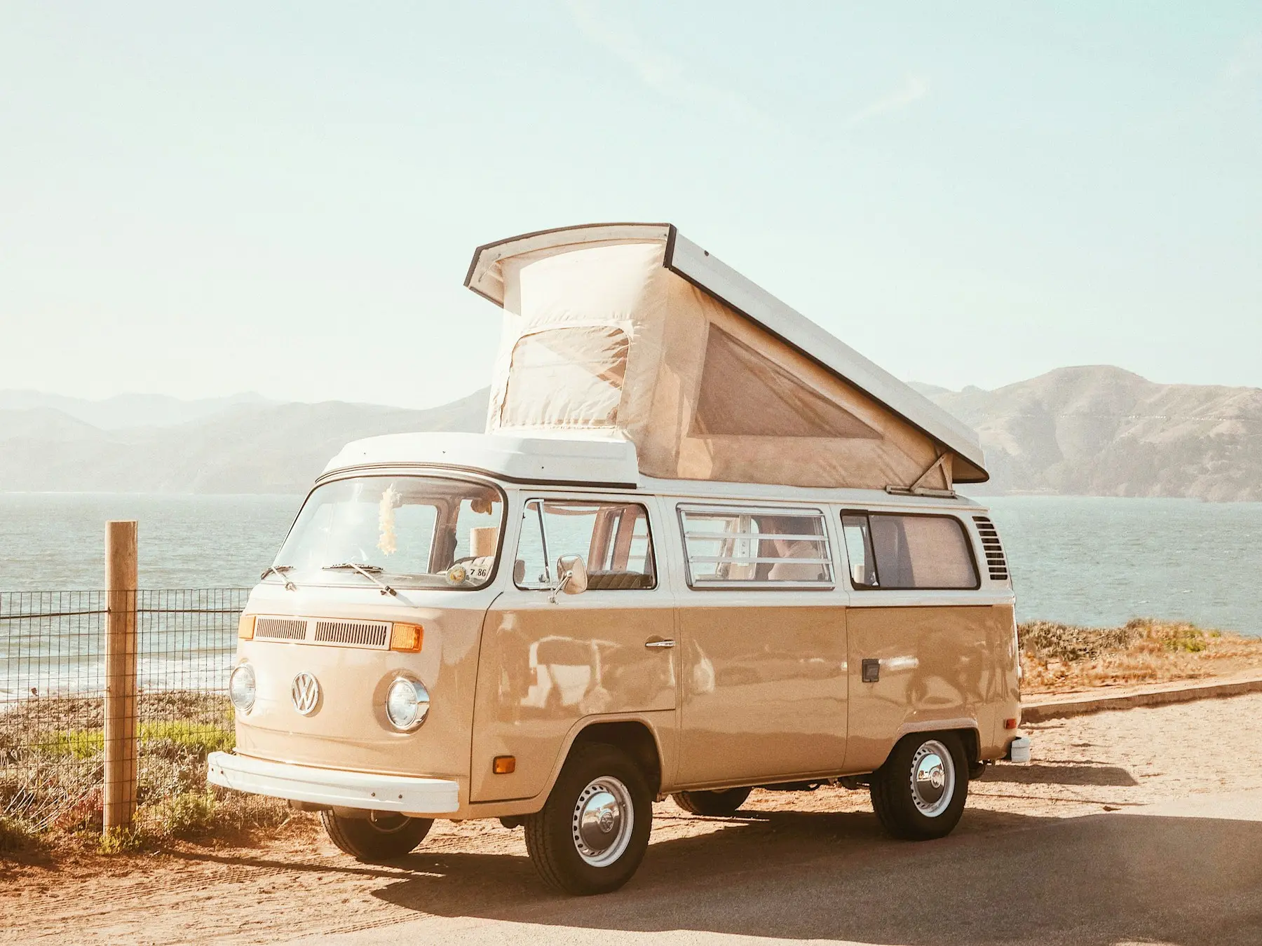 Vintage campervan parked by the sea with its roof popped up